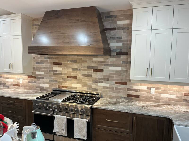Multi-coloured brick-style tile backsplash behind a range and wood range hood