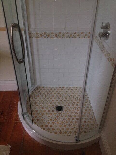 Corner shower with white subway tile walls, a penny round mosaic floor and a matching accent band